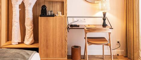 Habitación de hotel con armario de madera, escritorio con lámpara, silla y cama.
