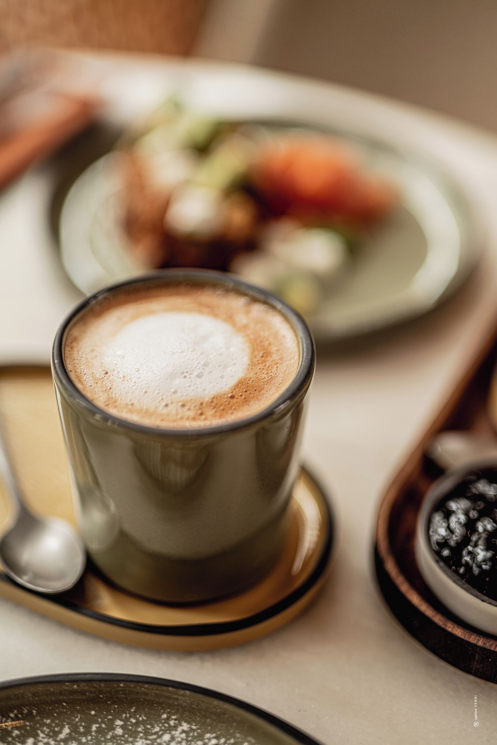 Een close-up van een kop koffie met schuim, op een schoteltje geplaatst.