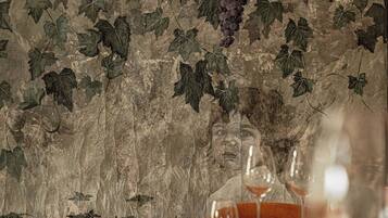 Una mesa con una copa de vino y un menú, frente a una pared con papel tapiz de parras.