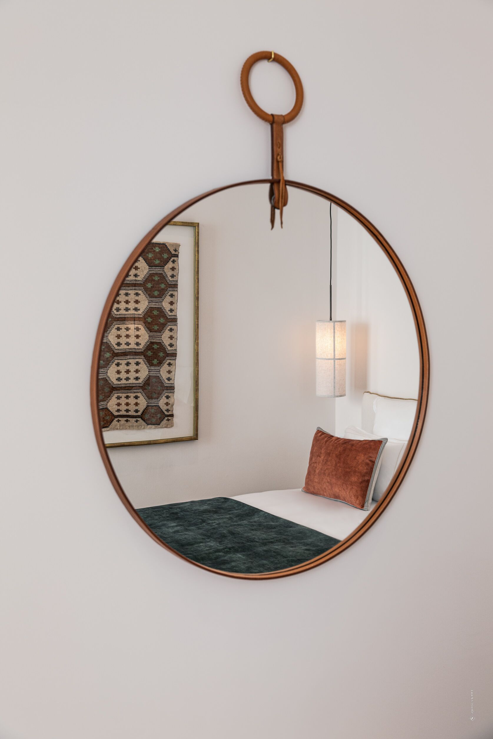 A circular mirror with a wooden frame hanging on a white wall.
