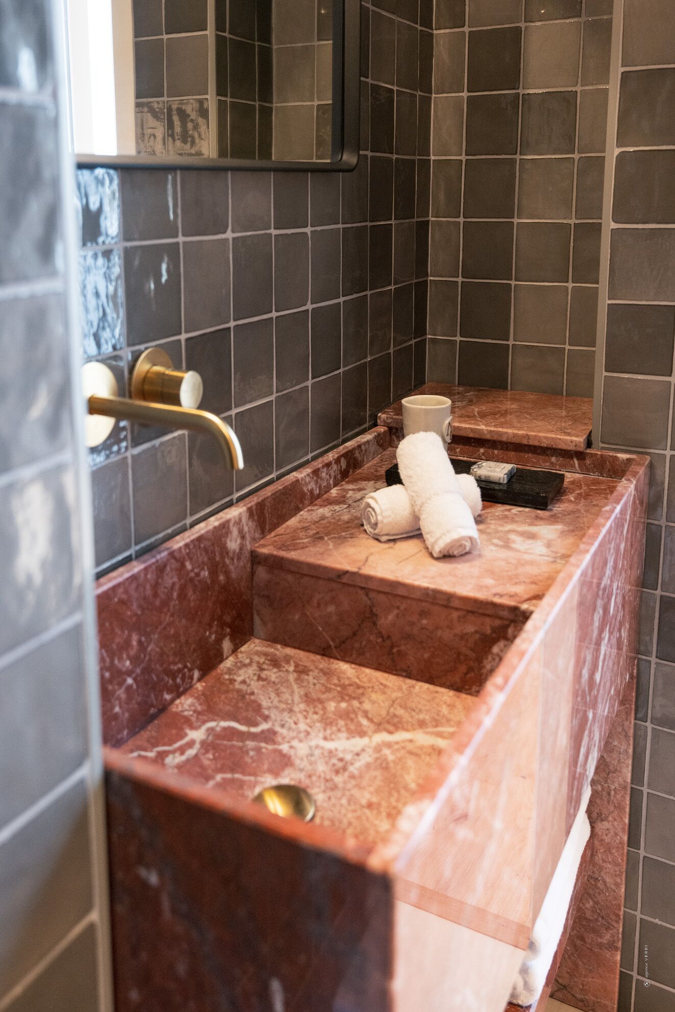 Une salle de bain avec un lavabo en marbre, un porte-serviettes et un miroir.