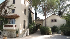 A building with a stone archway, a staircase, and a gravel driveway. - 2 -Studio Lierre Les Bastidières (Toulon)
