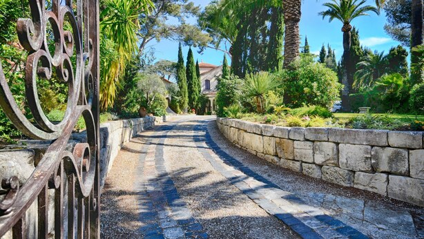 A paved pathway leading to a building, surrounded by stone walls and lush greenery. - 2 -Studio Lierre Les Bastidières (Toulon)