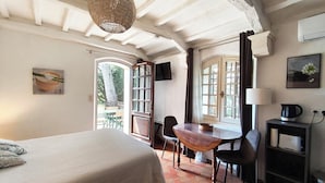 A bedroom with a bed, a wooden table, chairs, a desk with a lamp, and a TV. - 2 -Studio Lierre Les Bastidières (Toulon)