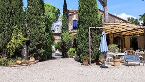 A courtyard with a pergola, seating, and a building with a bell tower. - 2 -Studio Lierre Les Bastidières (Toulon)