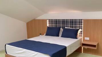 A bedroom with a bed, a nightstand, and a small shelf.