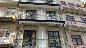 A multi-story building with balconies, a ground-level entrance, and a visible door number. - MyStay Porto São Bento (Porto)
