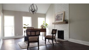 A spacious living room with a fireplace, a dining area with a table and chairs, and large windows allowing natural light. - Entire Home- Immaculate 5 bedrooms Sleeps 13 (Memphis)