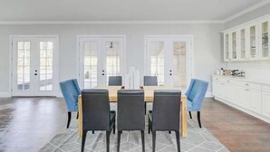 A dining room with a rectangular table, four chairs, and a white cabinet with glass doors. - Entire Home- Immaculate 5 bedrooms Sleeps 13 (Memphis)