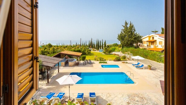 Vista de un área de piscina con varias piscinas, sillas de descanso y una terraza.