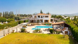 Una casa de dos pisos con piscina, un patio cubierto y vistas del paisaje circundante.