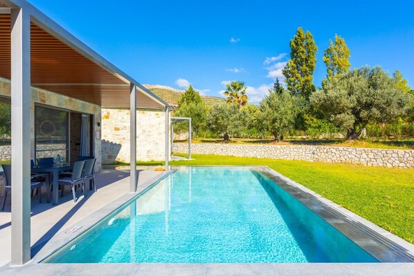 A modern outdoor pool area with a covered seating area and stone walls. - Villa Ersi - Three Bedroom Villa, Sleeps 6 (Ionian Islands)