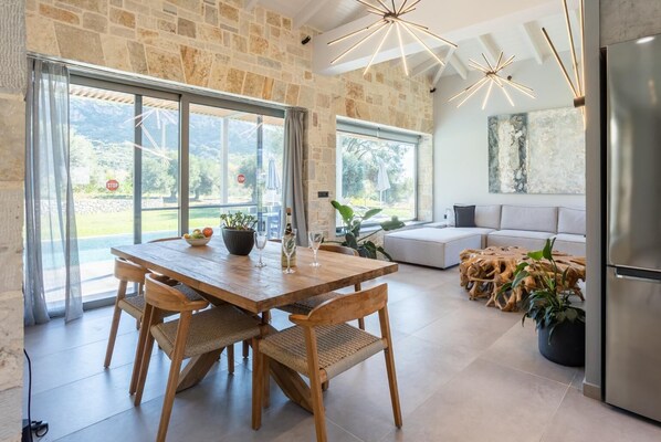 Una cocina moderna con una mesa de comedor de madera, paredes de piedra y ventanas amplias.