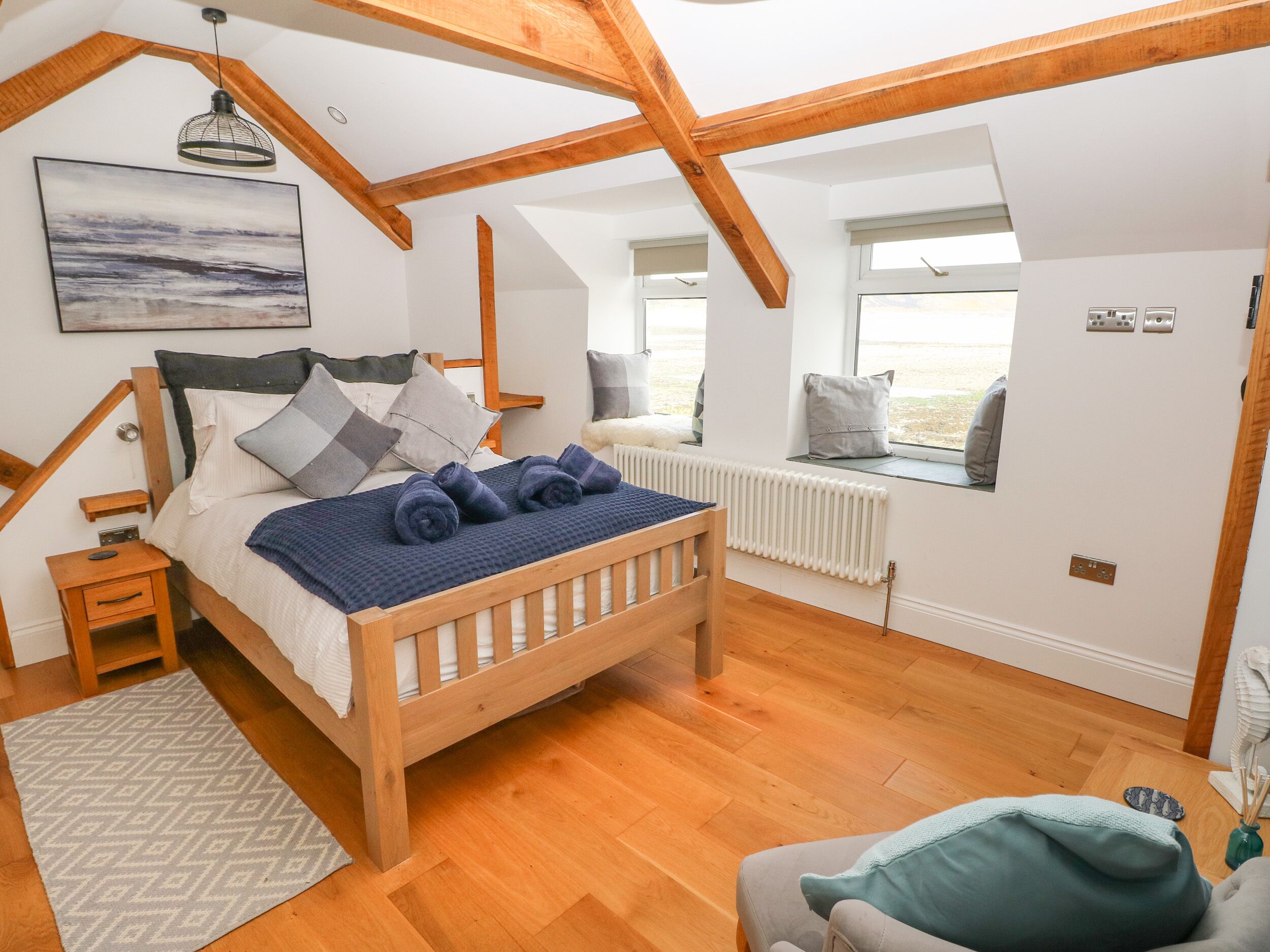 A bedroom with a wooden bed, a window seat, a radiator, and a view of the outdoors.