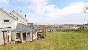 Une maison située sur la côte, dotée d’une terrasse, d’une vue sur la mer et d’une pelouse verdoyante.