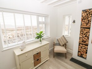 Ein Zimmer mit einem weißen Schrank, einem Blumentopf, einem Sessel mit Decke und einer Wanddekoration aus Holz.