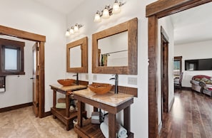 A bathroom with two wooden sinks, a large mirror, and a vanity with a bowl sink. - Glacier Country Chalet-Stunning Mountain Views (Columbia Falls)