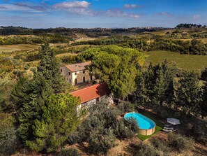Une maison entourée d’arbres, avec une piscine et du mobilier de jardin.