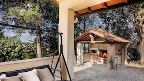 Eine Terrasse mit Schaukelstuhl und Kamin aus Stein.