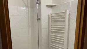 Et badeværelse med bruser, toilet og en træbænk.