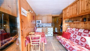 En kompakt bolig med tekøkken, spiseplads og sofa.