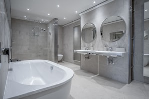 A modern bathroom with a freestanding bathtub, a double sink vanity, and a large mirror. - Bryn House - 5 Bed Home - Penmaen (Swansea)