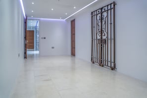 A hallway with a metal gate, a wooden door, and a tiled floor. - Bryn House - 5 Bed Home - Penmaen (Swansea)