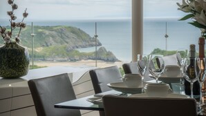 A table set for dining with a view of the ocean and hills. - Bryn House - 5 Bed Home - Penmaen (Swansea)