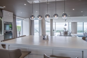 Uma cozinha moderna com uma ilha grande, eletrodomésticos de aço inoxidável e vista para o exterior.