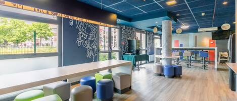 A modern interior with a long table, colorful stools, and a patterned wall.