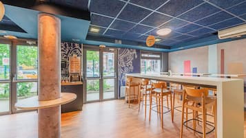 Un espace bar moderne avec une colonne centrale, des chaises en bois et un long comptoir.