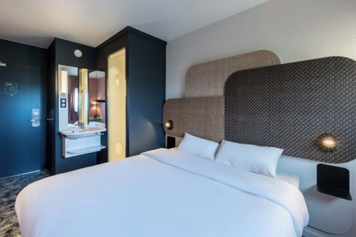 A hotel room with a large bed, a built-in vanity with a mirror, and two wall-mounted reading lights.