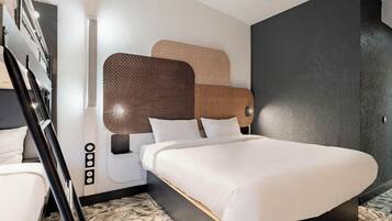 Een moderne hotelkamer met een groot bed, een houten hoofdeinde en een accentmuur in het zwart.