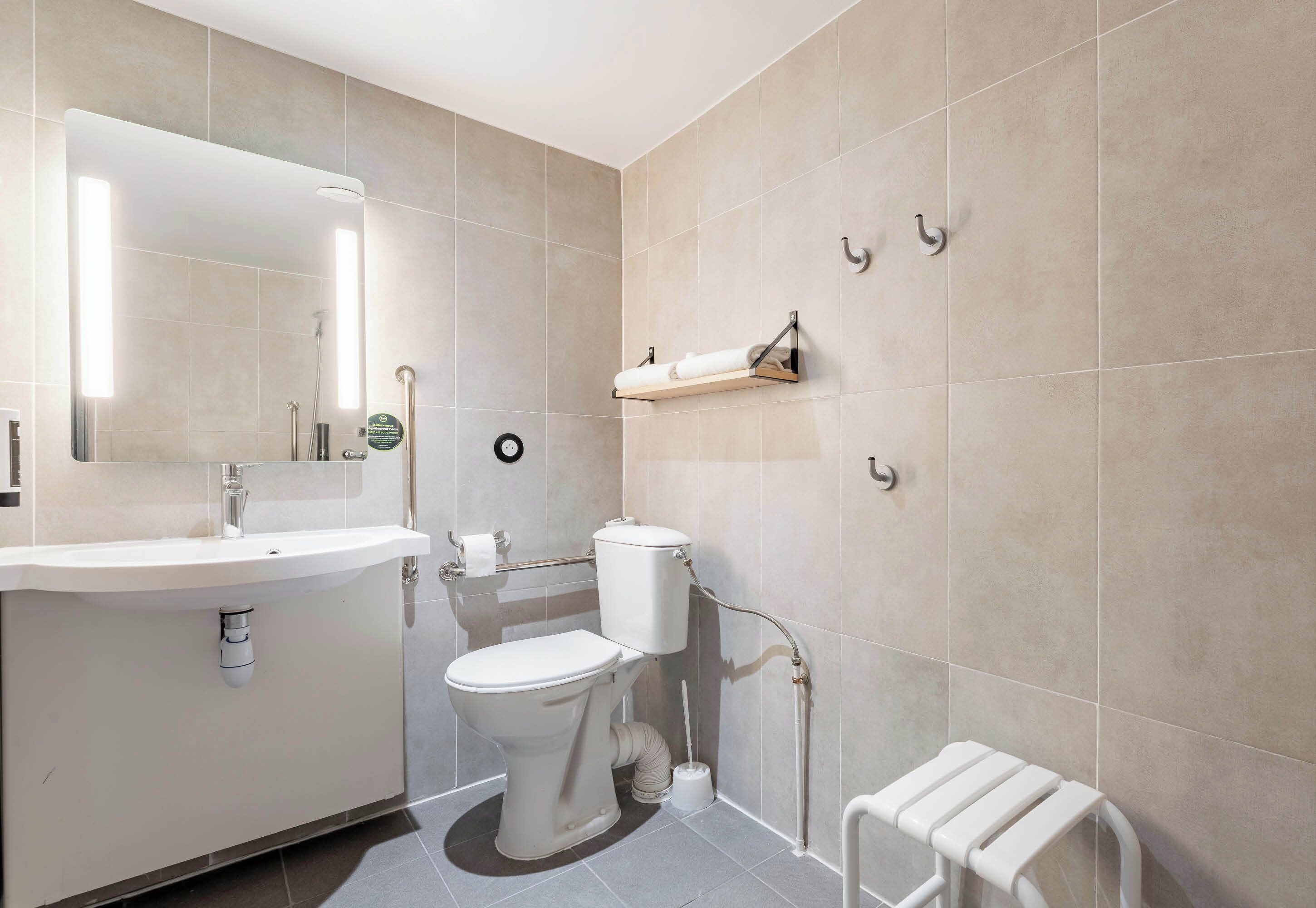 A modern bathroom with a white sink, toilet, and towel rack.