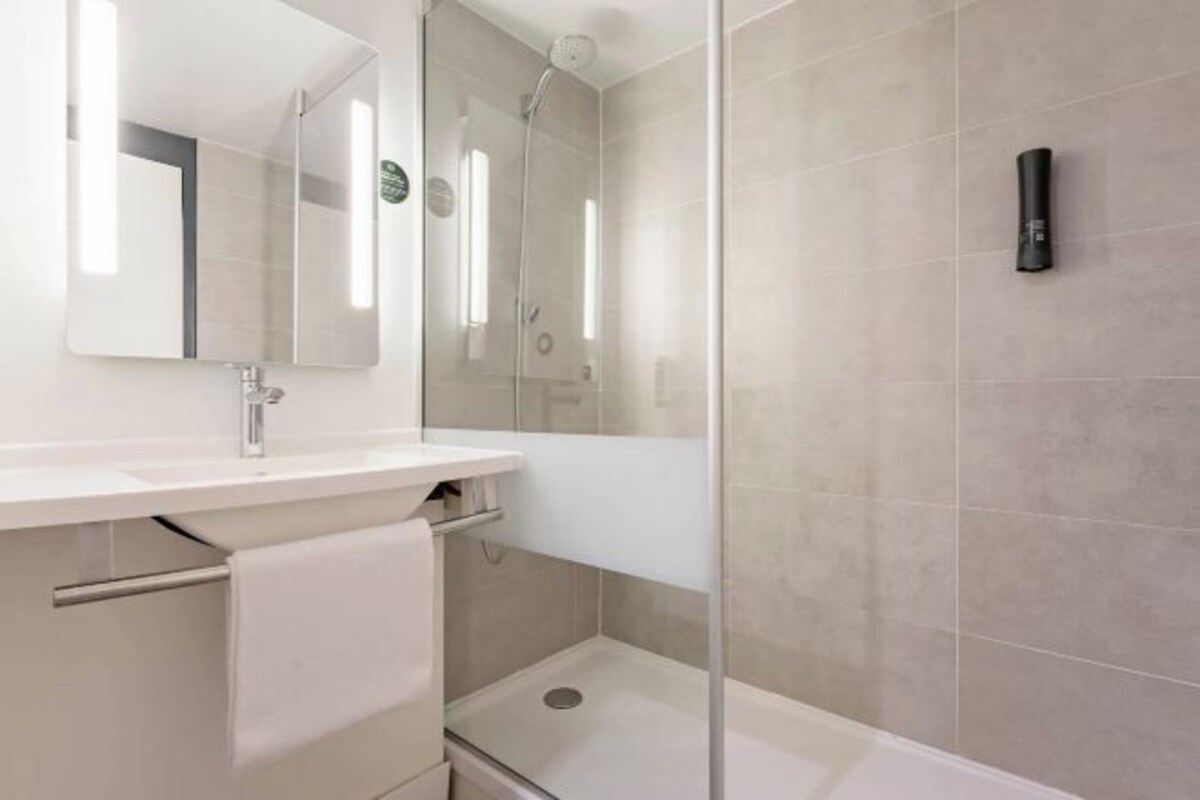 A modern bathroom with a glass-enclosed shower, a white sink, and a mirror.