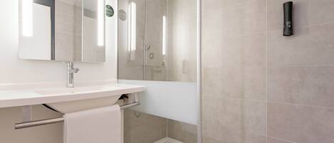 A modern bathroom with a glass-enclosed shower, a white sink with a mirror, and a towel rack.