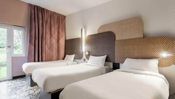 Une chambre d’hôtel avec deux lits, une grande fenêtre avec des rideaux et un mur décoré d’un motif.