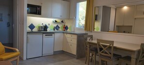 A compact kitchen with a microwave, toaster, and coffee maker. There is a dining area with a table and chairs.