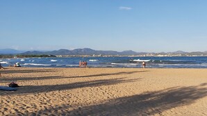 A beach with people, waves, and distant mountains.