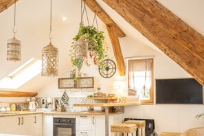 A cozy kitchen with wooden beams, hanging lanterns, and a clock on the wall.