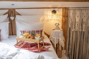 Un dormitorio acogedor con cabecera de madera, una mesita de noche con lámpara y una bandeja con alimentos para el desayuno.