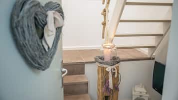 Un escalier doté d’une main courante en corde, un cadre photo fixé au mur et une petite table avec une bougie.