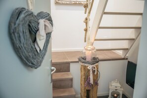 A staircase with a rope handrail, a wall-mounted picture frame, and a small table with a candle.