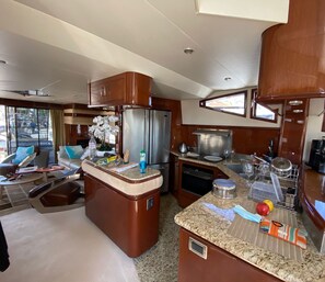 Cocina compacta con refrigerador, estufa y cafetera. Hay una zona de estar con mesa y sillas.