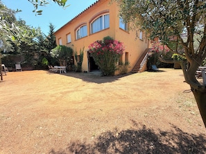 Una casa con patio, escaleras y jardín.