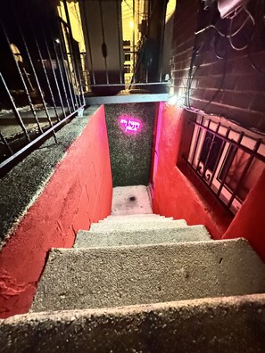 A staircase with red walls and a neon sign that reads "any happy place." - Executive Apartment at Uplands (Baltimore)