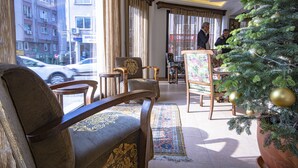 Um saguão de hotel com uma janela grande, uma árvore de Natal e uma área de estar com um tapete estampado.