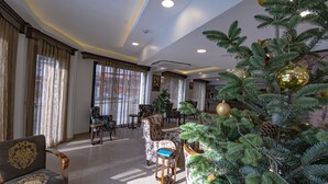 Uma sala de estar espaçosa com uma grande árvore de Natal, assentos confortáveis e um design de teto moderno.
