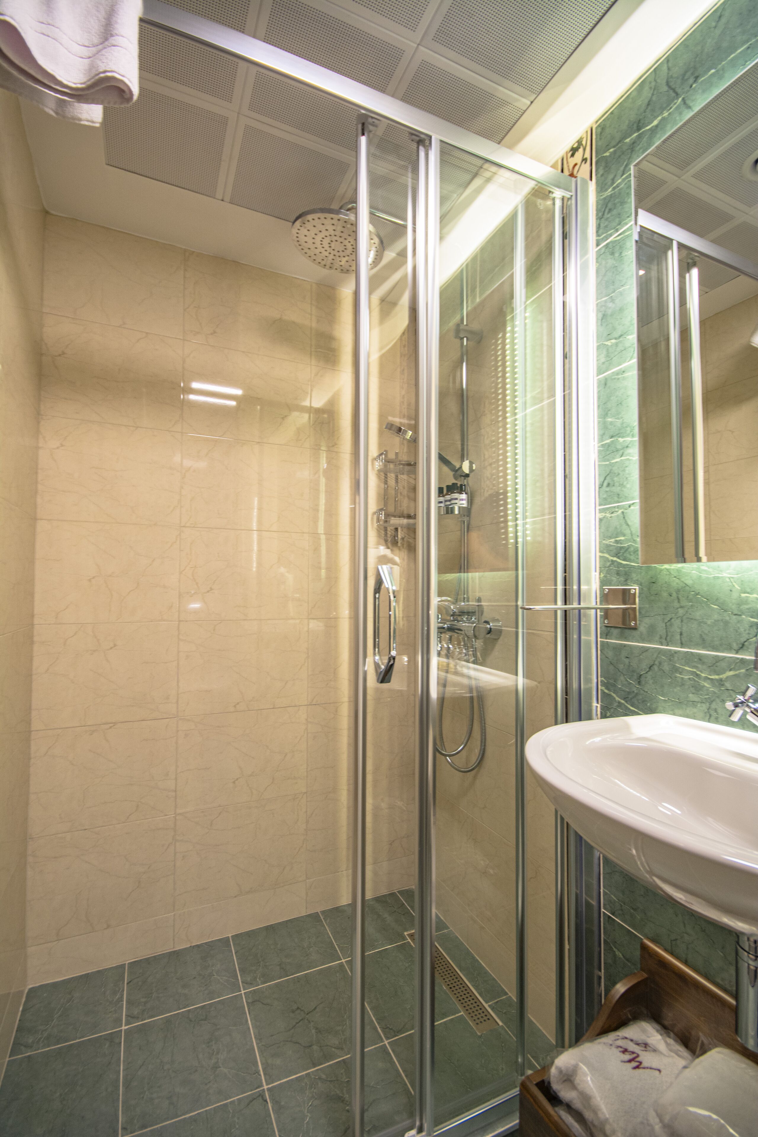 Une salle de bain moderne avec une douche à parois de verre, un lavabo et un mur recouvert de carreaux de marbre.
