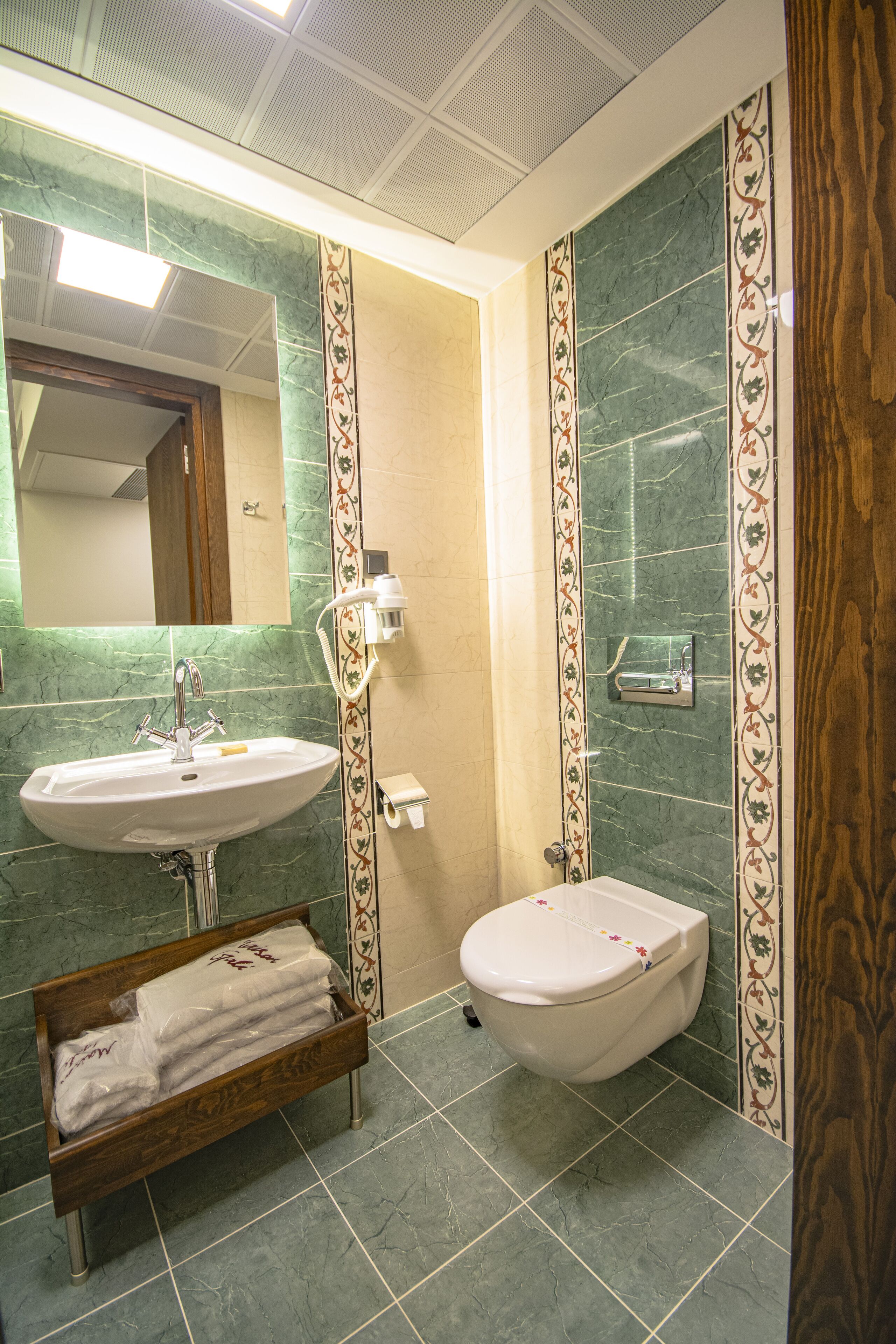 A bathroom with a sink, toilet, and a wooden shelf with towels.